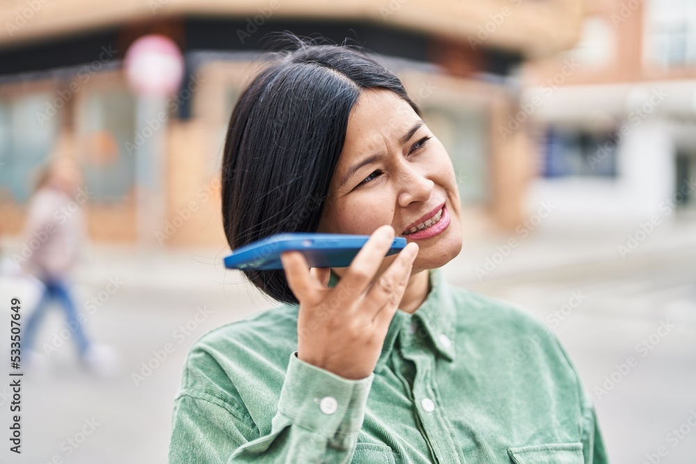 Fototapeta premium Young chinese woman talking on the smartphone at street