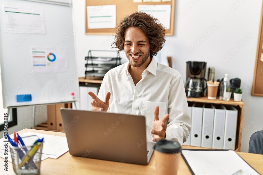 Young hispanic businessman having video call using laptop at office. Young hispanic businessman having video call using laptop at office.