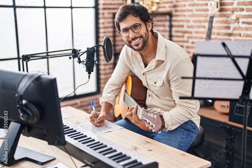 Vászonkép Young hispanic man musician composing song at music studio