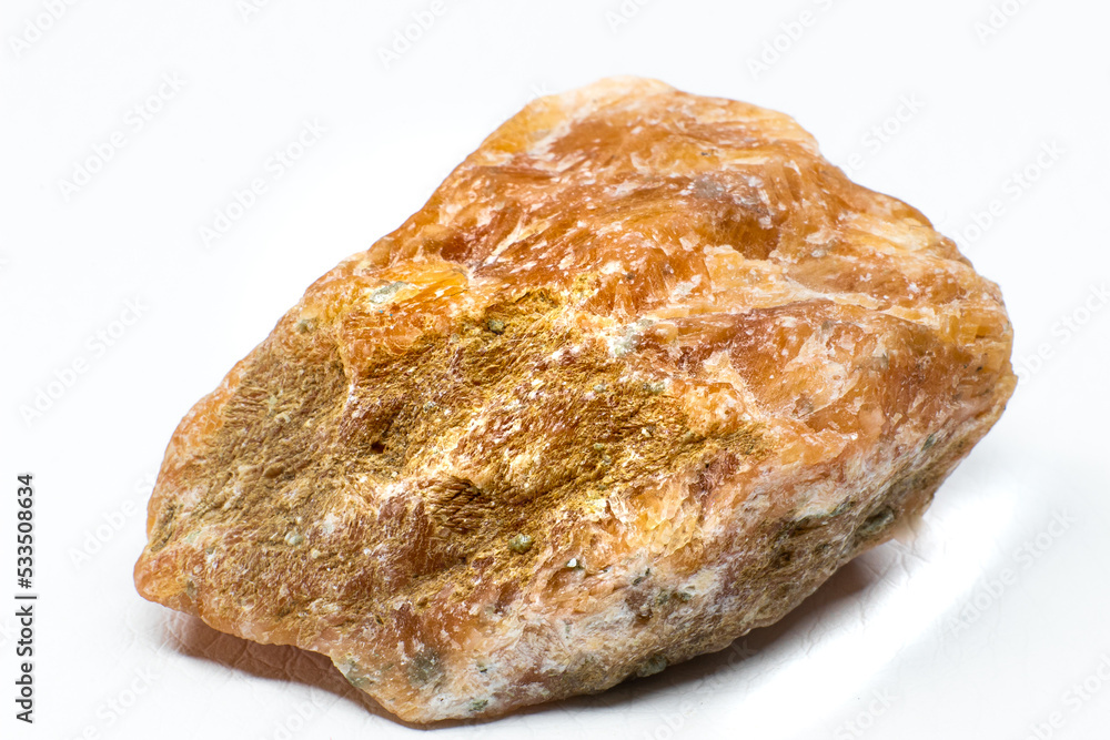 Raw orange calcite stone macro isolated on white background