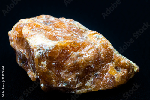 Foto Raw orange calcite stone macro isolated on black background