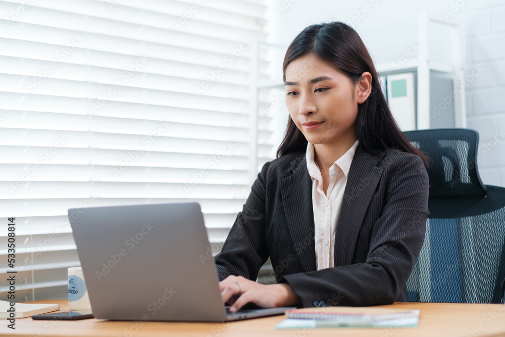 An Asian accountant businesswoman in office, financial worker using computer laptop preparing tax returns and accounts, monitoring expenditures and budget, auditing analyzing financial performance. An Asian accountant businesswoman in office, financial worker using computer laptop preparing tax returns and accounts, monitoring expenditures and budget, auditing analyzing financial performance.