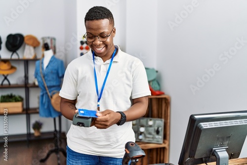 Fototapet Young african man working as shop assistance doing purchase at retail shop