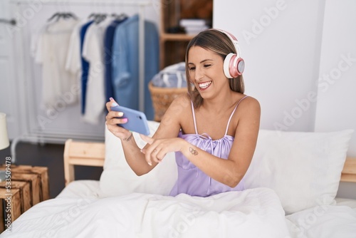 Slika na platnu Young beautiful hispanic woman watching video on smartphone sitting on bed at be