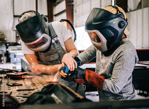 Εκτύπωση καμβά female welder teaches younger student welder how to weld