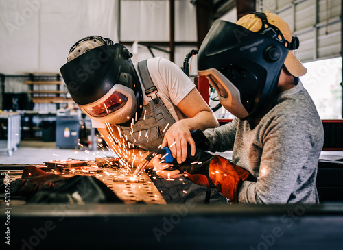 female welder teaches younger student welder how to weld