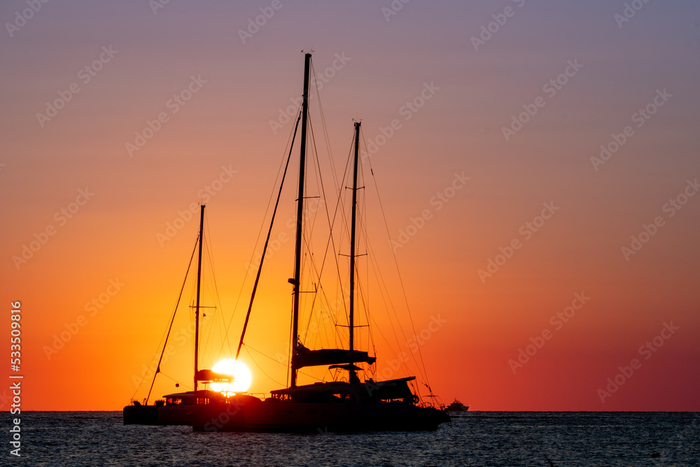 Two sailboats silhouetted by the sunset in the Mediterranean Sea