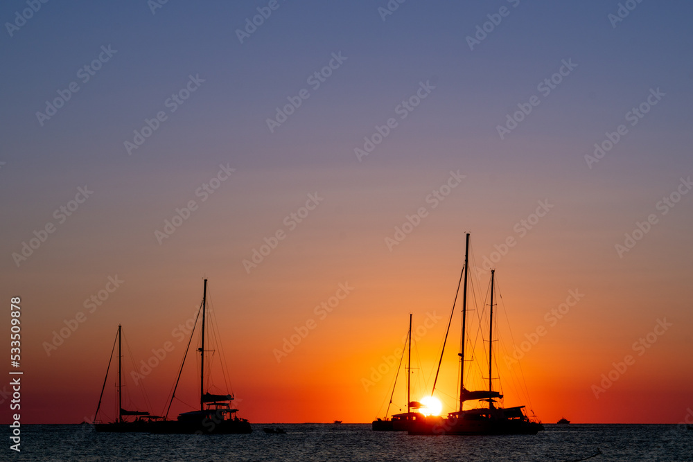 Three sailboats silhouetted by the sunset in the Mediterranean Sea