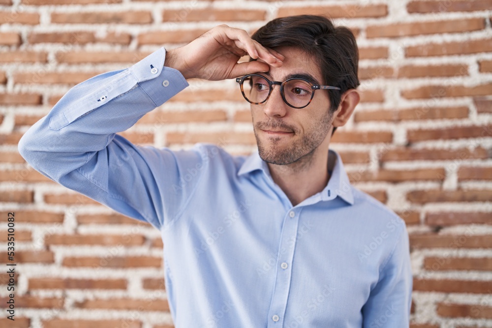 Young hispanic man standing over brick wall background worried and stressed about a problem with hand on forehead, nervous and anxious for crisis Young hispanic man standing over brick wall background worried and stressed about a problem with hand on forehead, nervous and anxious for crisis