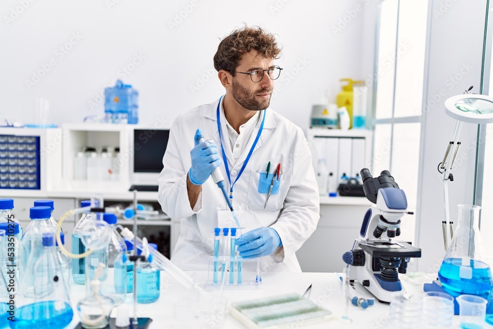 Young hispanic man wearing scientist uniform working at laboratory Young hispanic man wearing scientist uniform working at laboratory