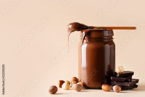 Fotografie Chocolate paste in jar with nuts on cut wooden board
