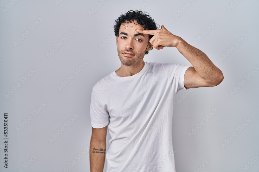Hispanic man standing over isolated background pointing unhappy to pimple on forehead, ugly infection of blackhead. acne and skin problem Hispanic man standing over isolated background pointing unhappy to pimple on forehead, ugly infection of blackhead. acne and skin problem