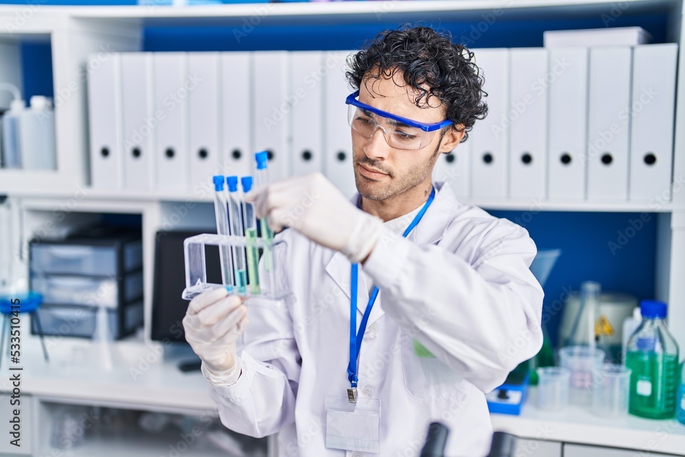 Young hispanic man scientist holding test tubes at laboratory Young hispanic man scientist holding test tubes at laboratory