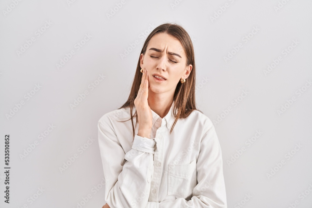 Young caucasian woman standing over isolated background touching mouth with hand with painful expression because of toothache or dental illness on teeth. dentist Young caucasian woman standing over isolated background touching mouth with hand with painful expression because of toothache or dental illness on teeth. dentist