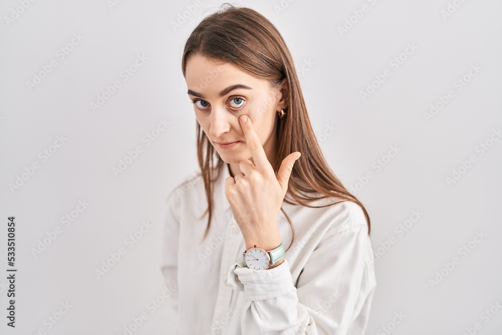 Young caucasian woman standing over isolated background pointing to the eye watching you gesture, suspicious expression Young caucasian woman standing over isolated background pointing to the eye watching you gesture, suspicious expression