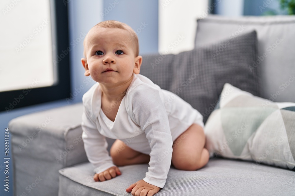 Adorable toddler sitting on sofa at home