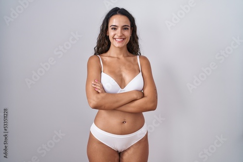 Young hispanic woman wearing white lingerie happy face smiling with crossed arms looking at the camera. positive person. © Krakenimages.com