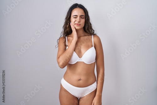Young hispanic woman wearing white lingerie touching mouth with hand with painful expression because of toothache or dental illness on teeth. dentist © Krakenimages.com