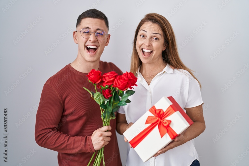 Mother and son holding mothers day gift smiling and laughing hard out loud because funny crazy joke. Mother and son holding mothers day gift smiling and laughing hard out loud because funny crazy joke.