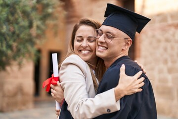 Man and woman mother and son hugging each other celebrating graduation at university