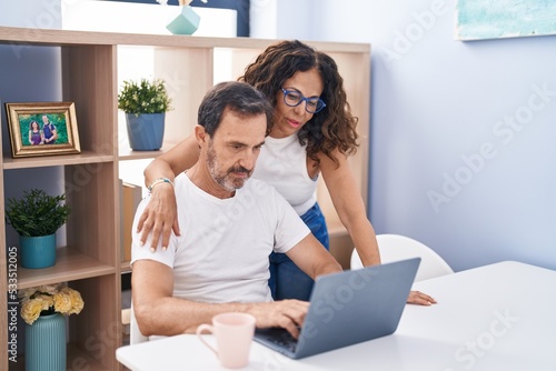 Man and woman couple using laptop with serious expression at home