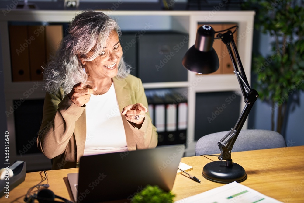 Middle age woman with grey hair working using computer laptop late at ...