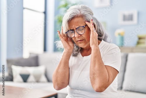 Middle age woman suffering for headache sitting on sofa at home