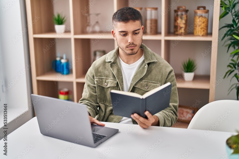 Young hispanic man sitting on table studying at home Young hispanic man sitting on table studying at home