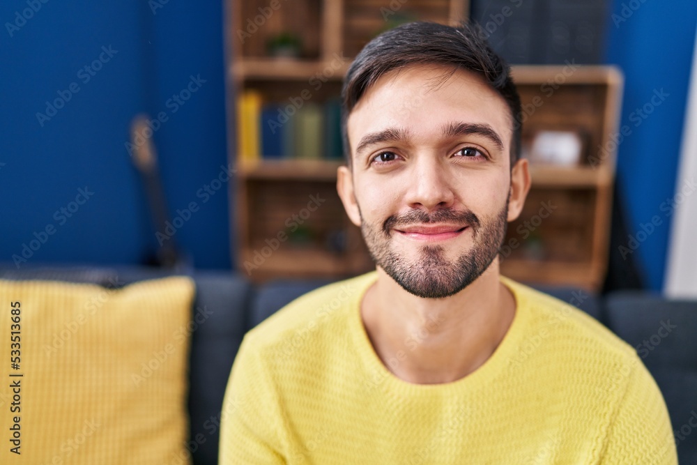 Obraz premium Young hispanic man smiling confident sitting on sofa at home