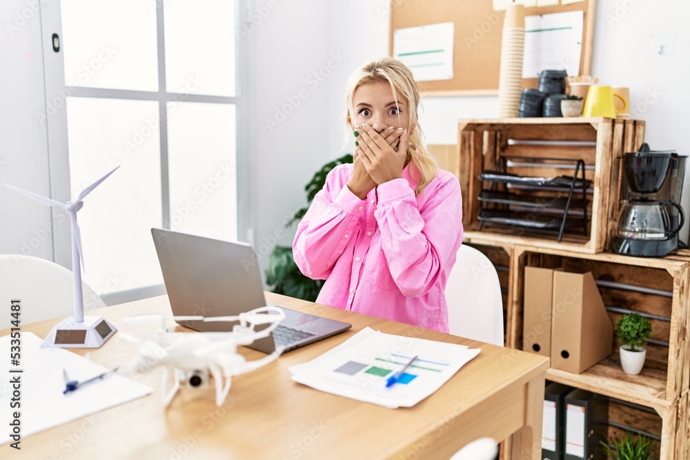 Young caucasian woman working at the office shocked covering mouth with hands for mistake. secret concept. Young caucasian woman working at the office shocked covering mouth with hands for mistake. secret concept.