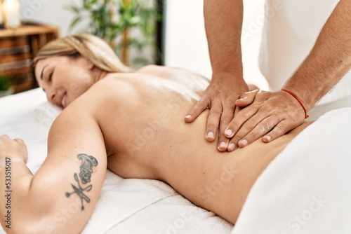 Young caucasian woman at physiotherapy clinic getting muscle massage by professional therapist. Physiotherapist man doing rehabilitation treatment to client