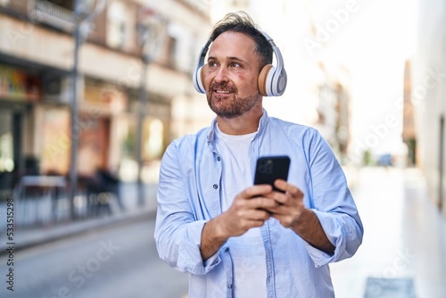 Young caucasian man smiling confident listening to music at street