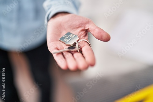 Young hispanic man holding key at new home