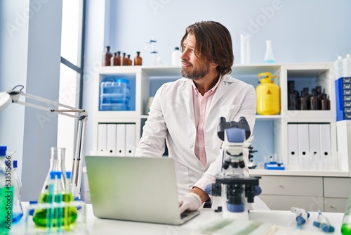 Middle age man scientist smiling confident using laptop at laboratory