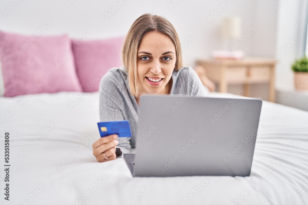 Young woman using laptop and credit card lying on bed at bedroom Young woman using laptop and credit card lying on bed at bedroom