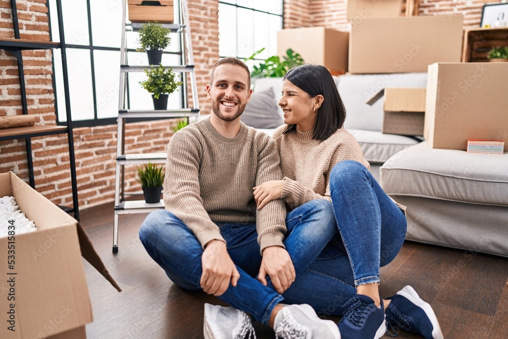 Man and woman couple hugging each other sitting on floor at new home Man and woman couple hugging each other sitting on floor at new home