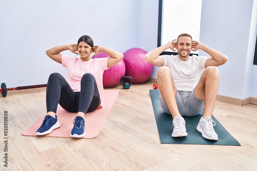 Man and woman couple smiling confident training abs exercise at sport center Man and woman couple smiling confident training abs exercise at sport center