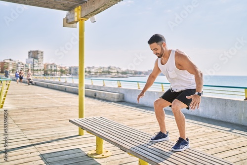 Hispanic man working out jumping a bench outdoors on a sunny day