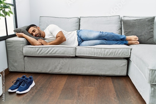 Young hispanic man lying on sofa sleeping at home