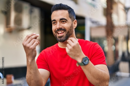 Young hispanic man smiling confident speaking at street