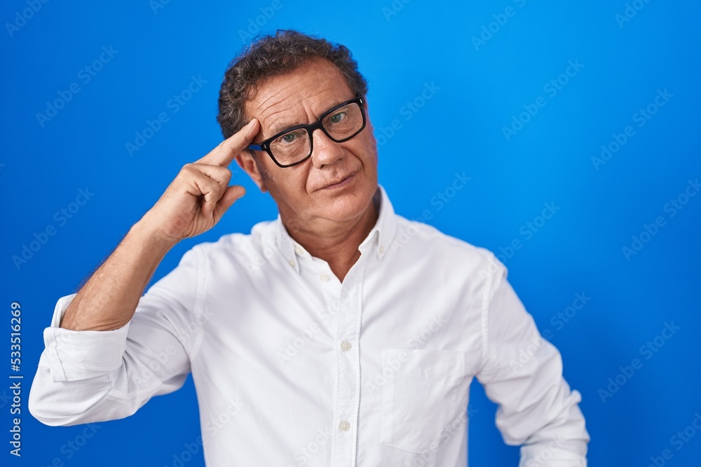 Middle age hispanic man standing over blue background shooting and killing oneself pointing hand and fingers to head like gun, suicide gesture. Middle age hispanic man standing over blue background shooting and killing oneself pointing hand and fingers to head like gun, suicide gesture.