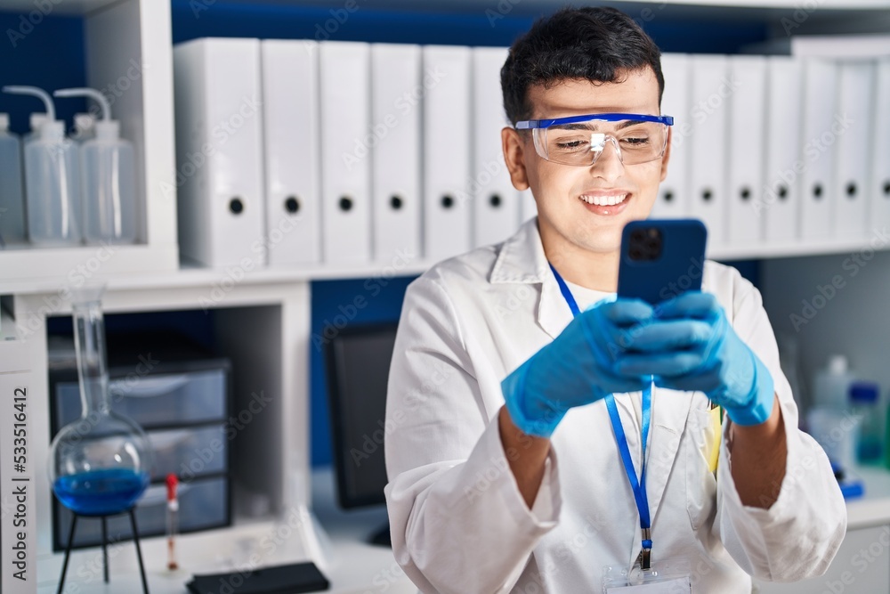 Young non binary man scientist smiling confident using smartphone at laboratory Young non binary man scientist smiling confident using smartphone at laboratory
