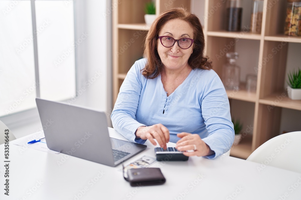 Senior woman using laptop and calculator at home Senior woman using laptop and calculator at home