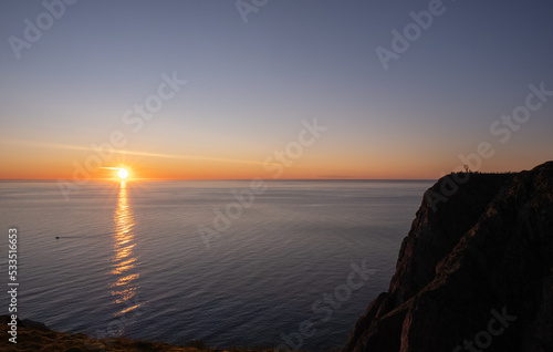 Wonderful landscapes in Norway. Nord-Norge. Beautiful scenery of a midnight sun sunset at Nordkapp (Cape North). Boat and globe on a cliff. Rippled sea and clear orange sky. Selective focus © Maurizio