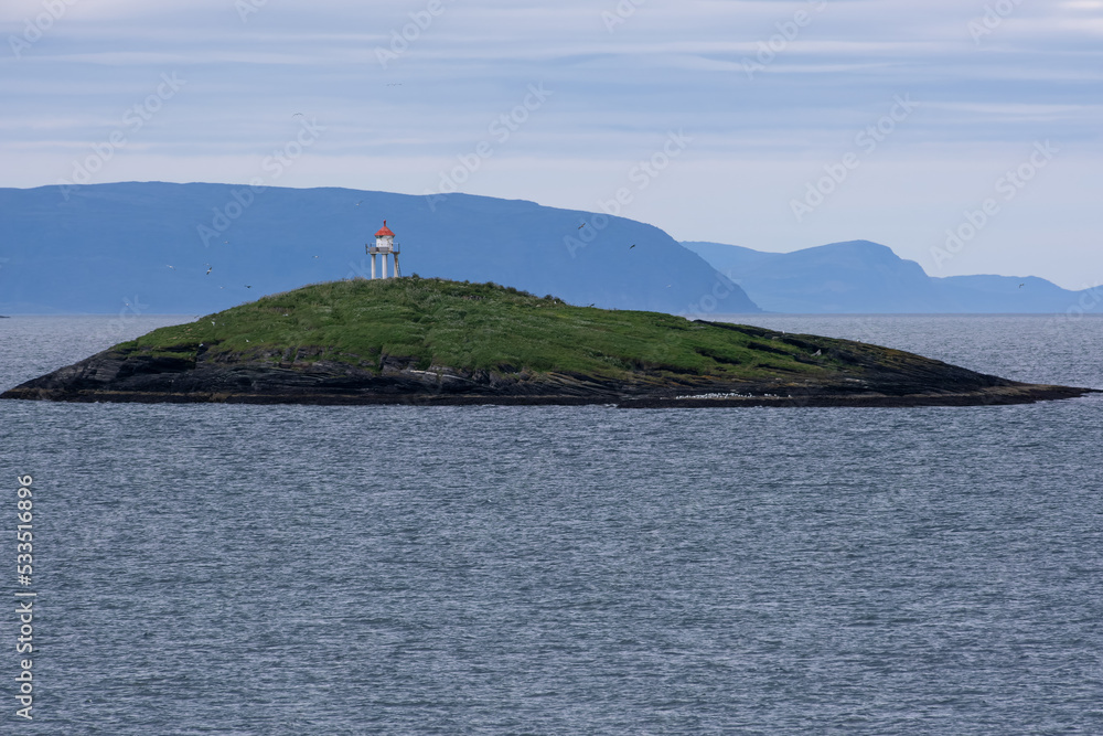 Wonderful landscapes in Norway. Nord-Norge. Masholmen Island Lighthouse. Scenic coastline in the north of Norway, Europe. Rocky skerries, seagulls. Islands in background. Rippled sea. Selective focus