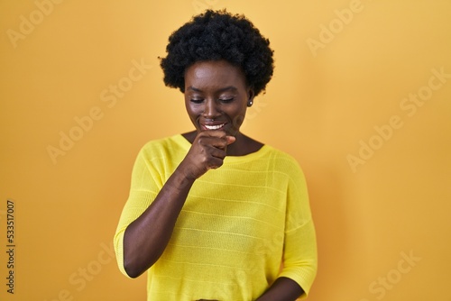 African young woman standing over yellow studio feeling unwell and coughing as symptom for cold or bronchitis. health care concept. © Krakenimages.com