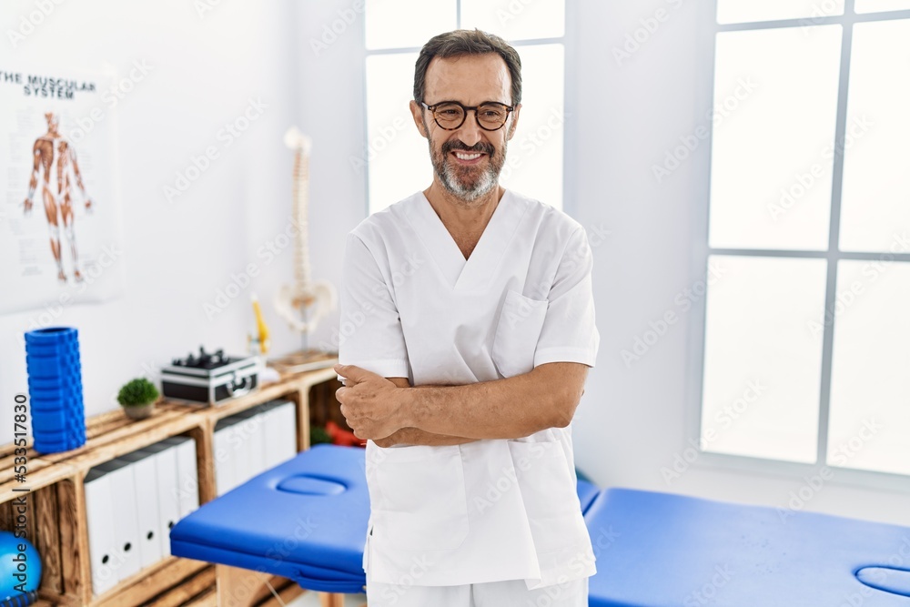 Middle age man with beard working at pain recovery clinic happy face smiling with crossed arms looking at the camera. positive person. Middle age man with beard working at pain recovery clinic happy face smiling with crossed arms looking at the camera. positive person.