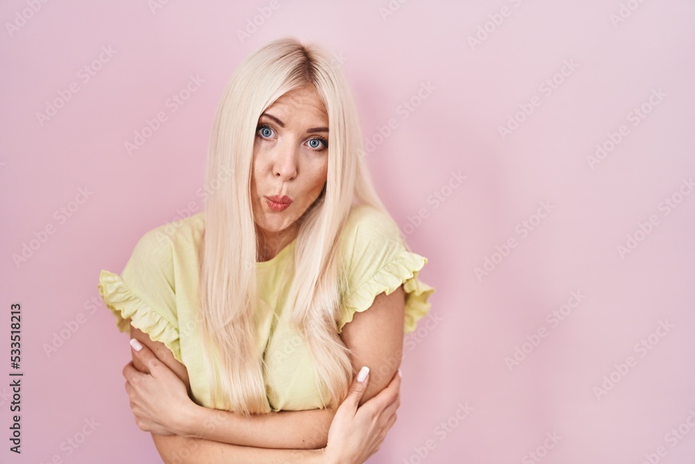Caucasian woman standing over pink background shaking and freezing for winter cold with sad and shock expression on face Caucasian woman standing over pink background shaking and freezing for winter cold with sad and shock expression on face