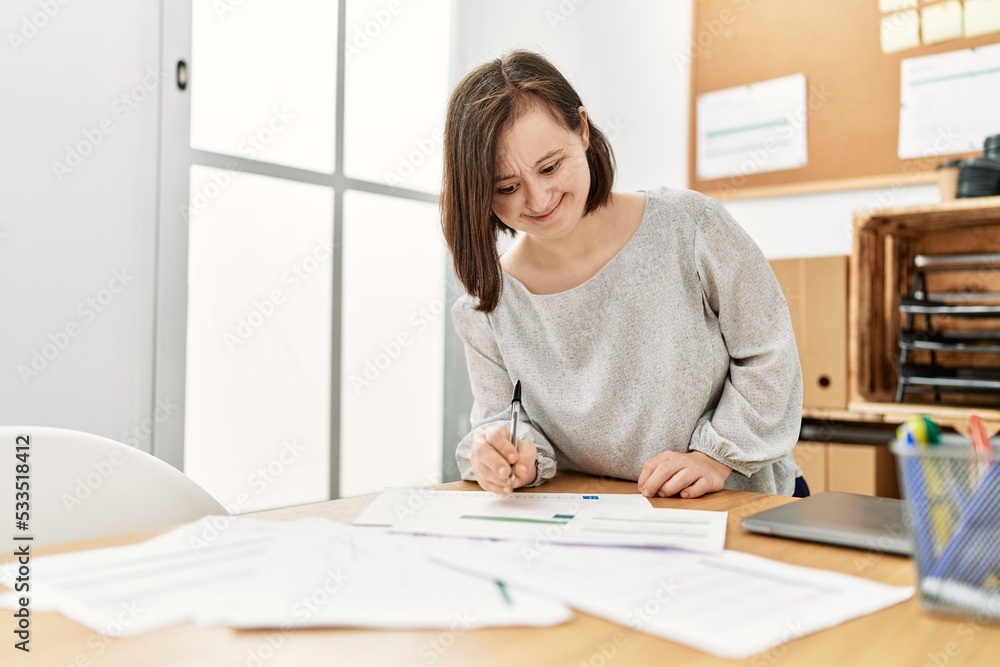 Brunette woman with down syndrome working with documents at business office Brunette woman with down syndrome working with documents at business office