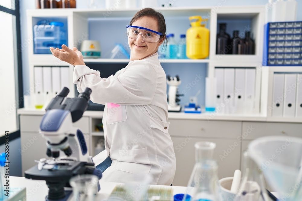 Hispanic girl with down syndrome working at scientist laboratory pointing aside with hands open palms showing copy space, presenting advertisement smiling excited happy Hispanic girl with down syndrome working at scientist laboratory pointing aside with hands open palms showing copy space, presenting advertisement smiling excited happy